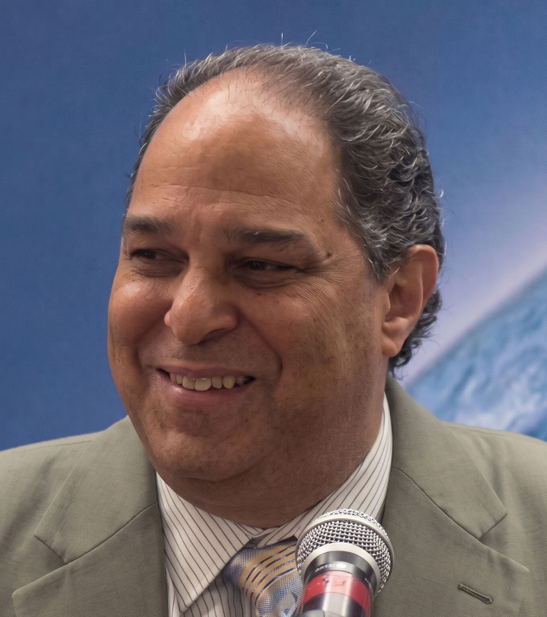 Dr. Frank Kaufmann speaking at a podium with Earth in the background