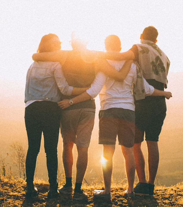 Friends with arms around one another at sunset